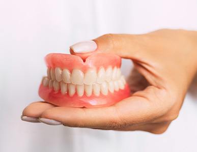 dentist holding dentures in hand