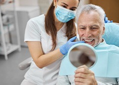 man smiling while looking in dental mirror