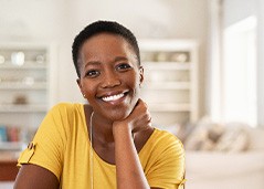 Woman in yellow shirt smiling at home