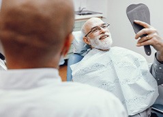 Man smiling at reflection in handheld mirror