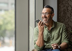 Man smiling while talking on phone and looking out window