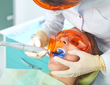 Dentist hardening patient’s filling with UV light