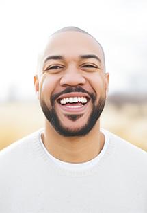 Man in white shirt smiling outside