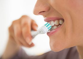 Nose-to-chin profile view of a woman brushing her top teeth